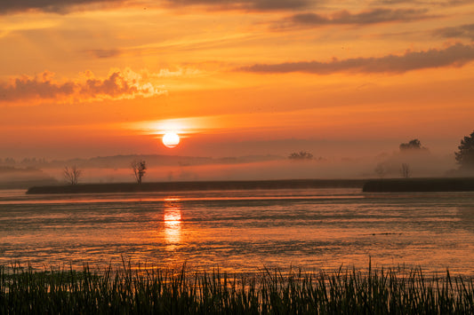 Sunset over a misty lake with orange and purple hues